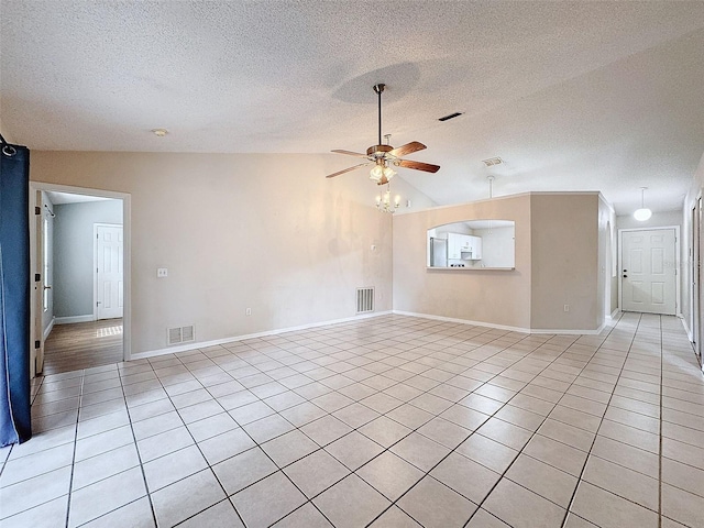 tiled empty room with a textured ceiling, ceiling fan, and vaulted ceiling