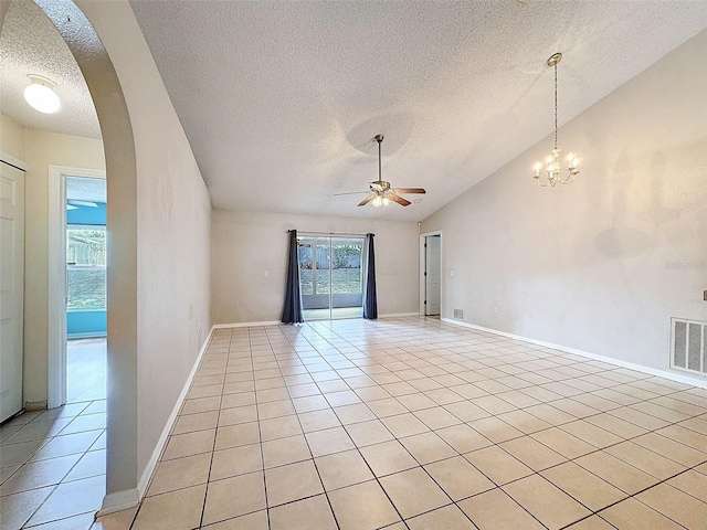 empty room featuring vaulted ceiling, light tile patterned floors, ceiling fan with notable chandelier, and a textured ceiling