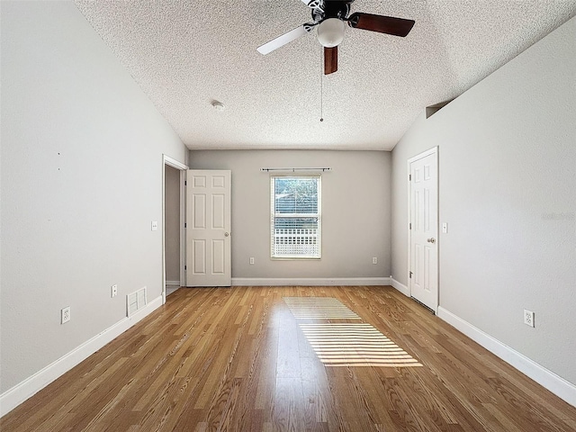 empty room featuring a textured ceiling, light hardwood / wood-style flooring, ceiling fan, and vaulted ceiling