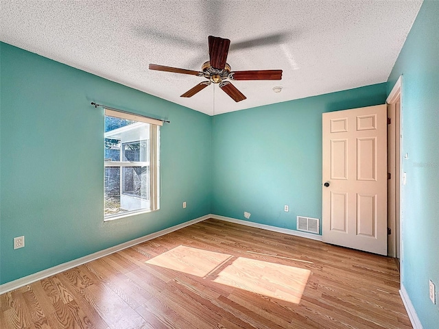 empty room with a textured ceiling, light wood-type flooring, and ceiling fan