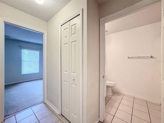 bathroom with toilet, a textured ceiling, and tile patterned floors