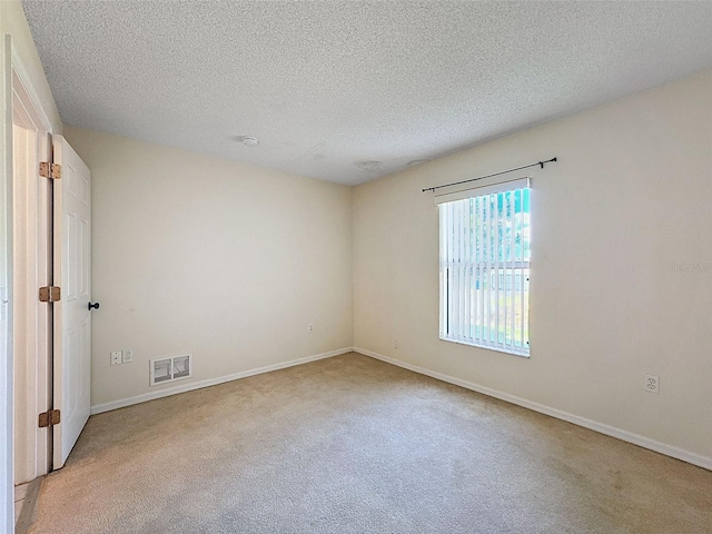 spare room with light colored carpet and a textured ceiling