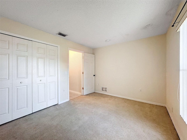 unfurnished bedroom featuring a closet, light colored carpet, and a textured ceiling