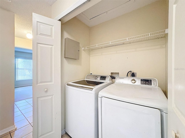 clothes washing area with washing machine and clothes dryer, light tile patterned flooring, and a textured ceiling