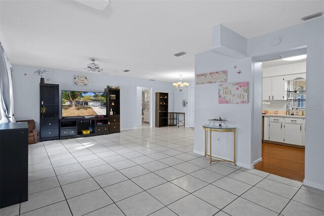 tiled living room with ceiling fan with notable chandelier