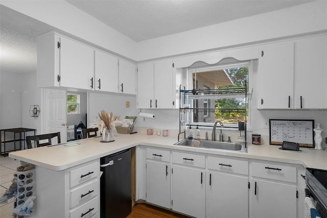 kitchen with kitchen peninsula, stainless steel dishwasher, a textured ceiling, sink, and white cabinets