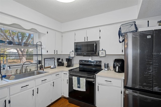 kitchen with white cabinets, sink, appliances with stainless steel finishes, and a textured ceiling