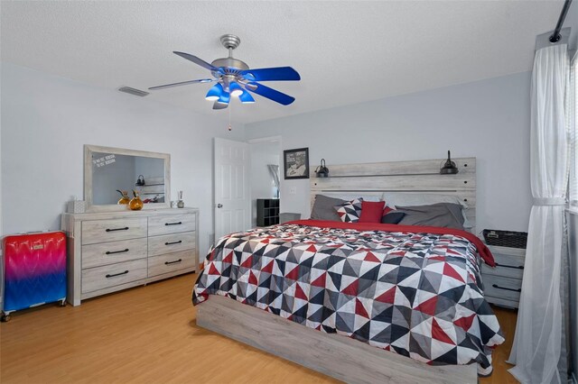 bedroom featuring ceiling fan, light hardwood / wood-style flooring, and a textured ceiling