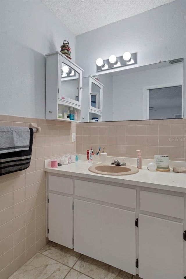 bathroom featuring tile walls, vanity, and a textured ceiling