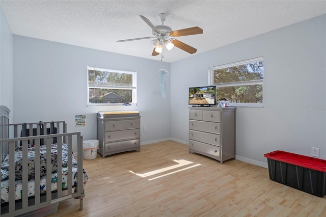 bedroom with ceiling fan, light wood-type flooring, and a textured ceiling