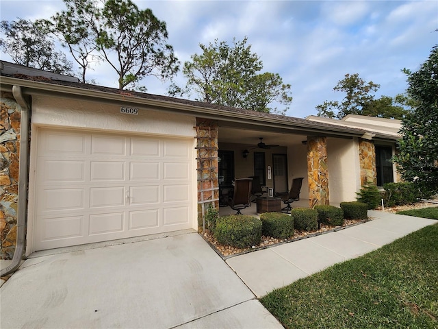 single story home with ceiling fan, covered porch, and a garage