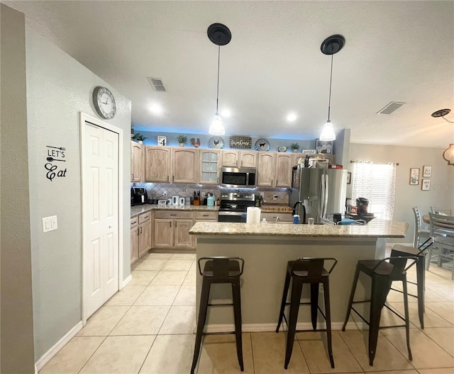 kitchen with a breakfast bar, light tile patterned floors, decorative backsplash, and appliances with stainless steel finishes