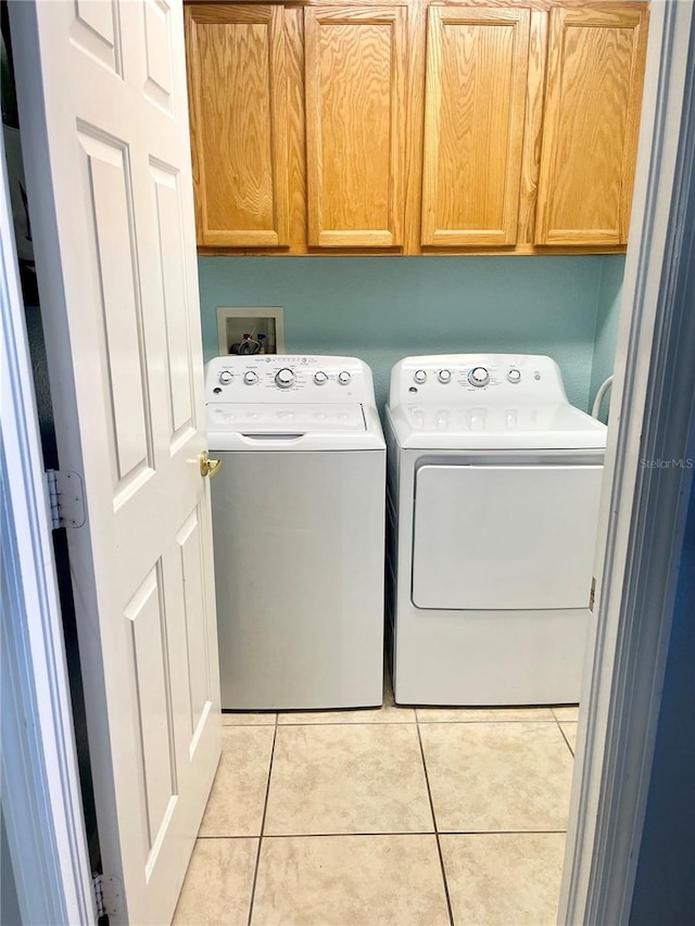 laundry room featuring light tile patterned flooring, cabinets, and washing machine and dryer