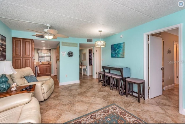 living room featuring ceiling fan and a textured ceiling