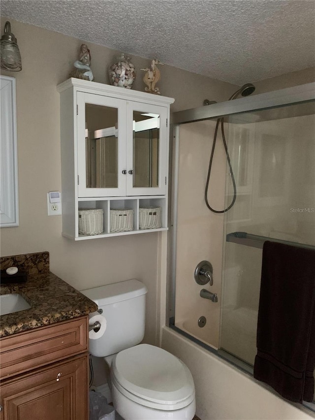 full bathroom with combined bath / shower with glass door, vanity, a textured ceiling, and toilet