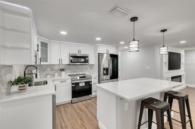 kitchen featuring white cabinetry, sink, light hardwood / wood-style flooring, backsplash, and appliances with stainless steel finishes