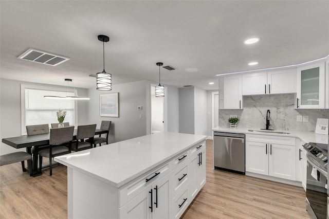 kitchen featuring hanging light fixtures, white cabinetry, sink, and stainless steel appliances