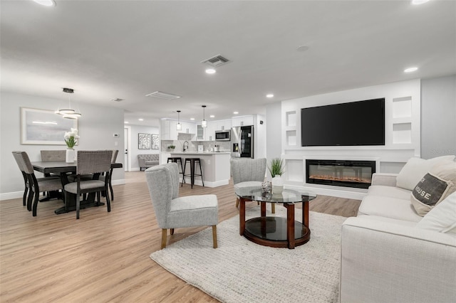 living room featuring sink and light hardwood / wood-style flooring