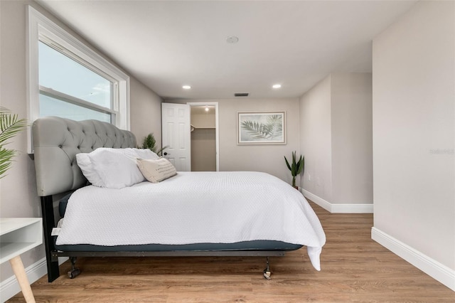 bedroom with light wood-type flooring, a walk in closet, and a closet