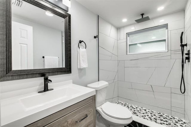 bathroom with vanity, toilet, and tiled shower