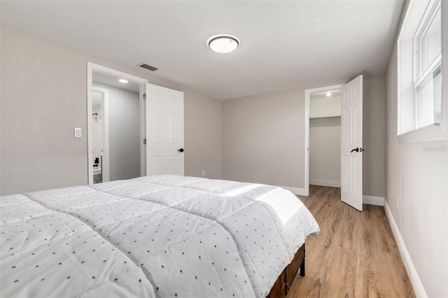 bedroom with a walk in closet, a closet, and light hardwood / wood-style floors