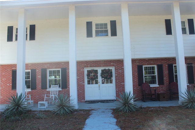 townhome / multi-family property with a porch and brick siding