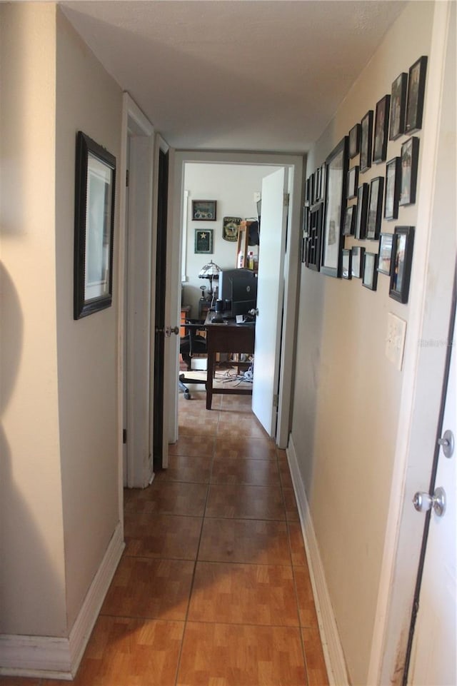 hall with dark tile patterned floors and baseboards