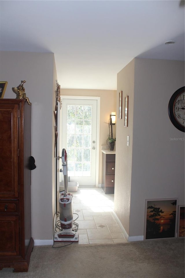 hall with baseboards and light colored carpet