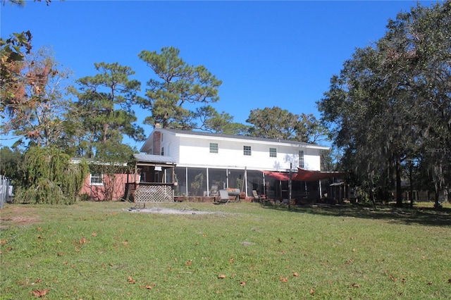 back of property with a sunroom, a chimney, and a yard