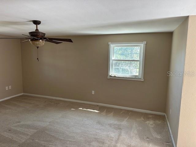 unfurnished room with carpet flooring, ceiling fan, and baseboards