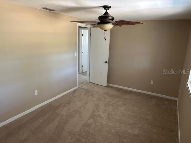 spare room featuring baseboards, a ceiling fan, visible vents, and light colored carpet