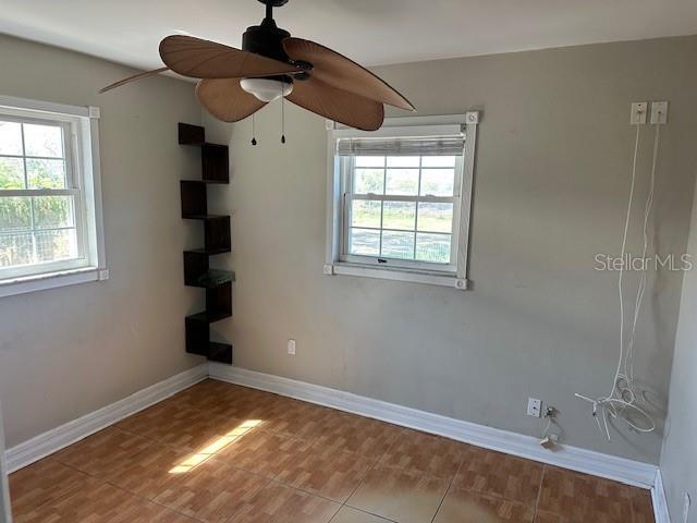 spare room featuring a ceiling fan and baseboards