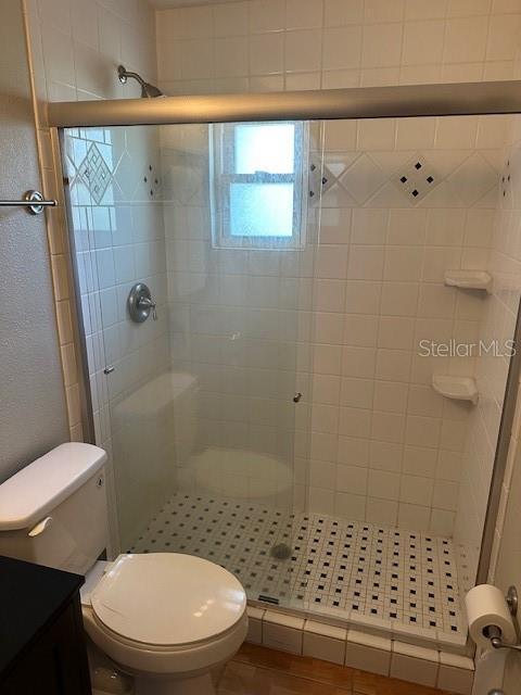 full bath with vanity, a shower stall, and toilet