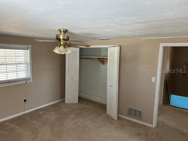 unfurnished bedroom with carpet floors, a closet, visible vents, ceiling fan, and baseboards