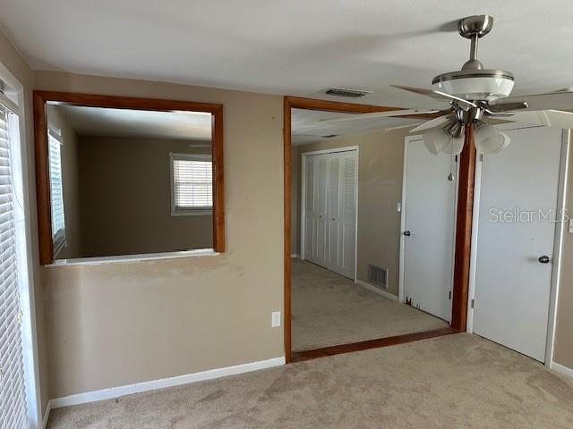 carpeted empty room featuring visible vents and baseboards