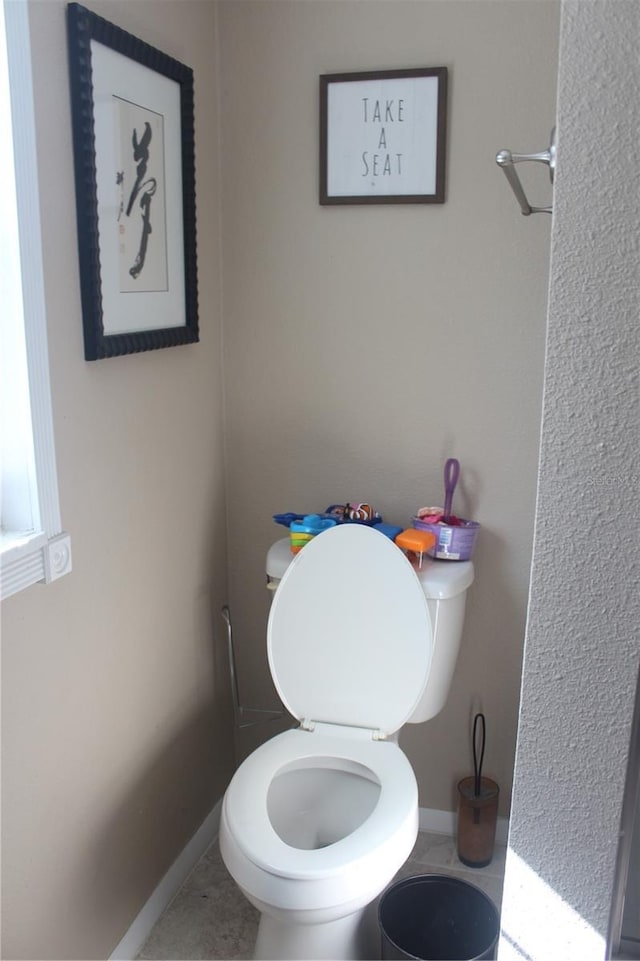 bathroom with tile patterned flooring, baseboards, and toilet