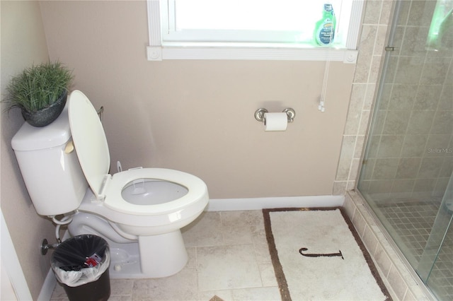 bathroom with baseboards, a shower stall, and toilet