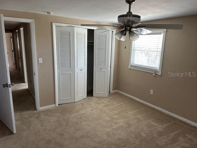 unfurnished bedroom featuring a ceiling fan, a closet, light carpet, and baseboards