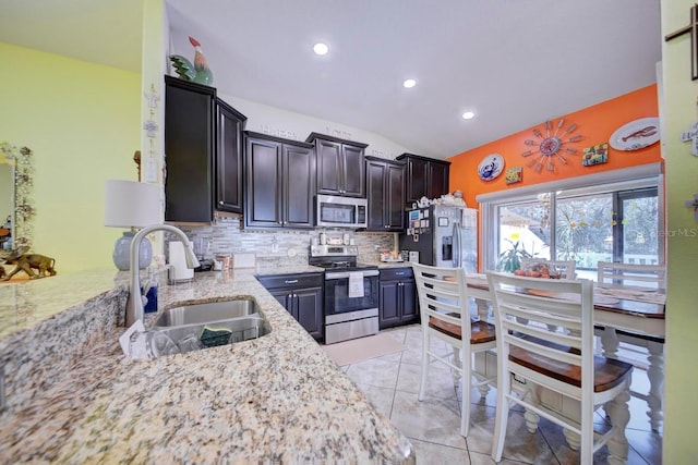 kitchen featuring lofted ceiling, sink, light tile patterned floors, appliances with stainless steel finishes, and tasteful backsplash