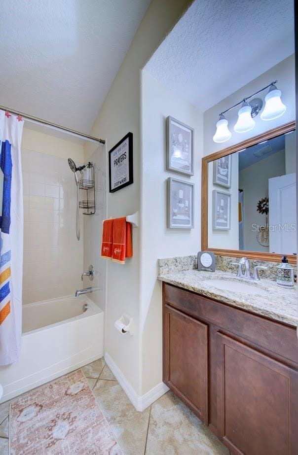 bathroom with tile patterned floors, vanity, shower / bathtub combination with curtain, and a textured ceiling