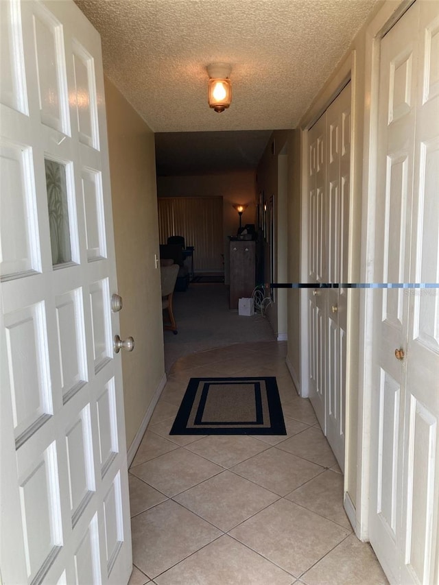 hallway featuring light tile patterned floors and a textured ceiling