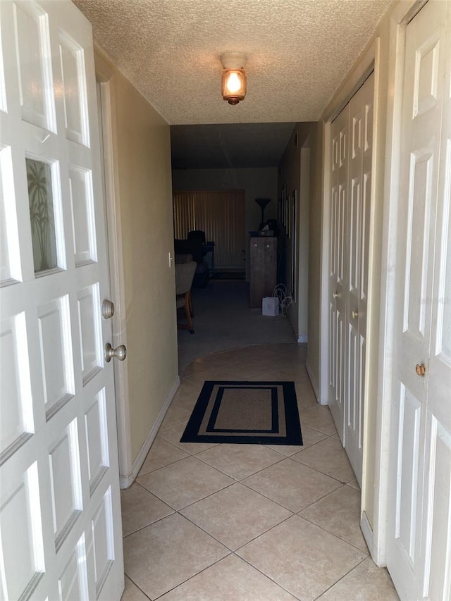 hall with light tile patterned floors and a textured ceiling