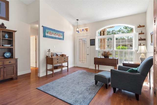 living area with a textured ceiling, dark hardwood / wood-style floors, an inviting chandelier, and high vaulted ceiling