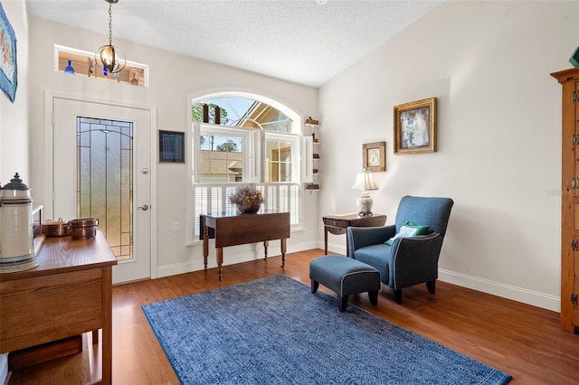 entrance foyer with lofted ceiling, hardwood / wood-style floors, a textured ceiling, and an inviting chandelier