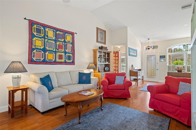 living room featuring wood-type flooring, a textured ceiling, and vaulted ceiling