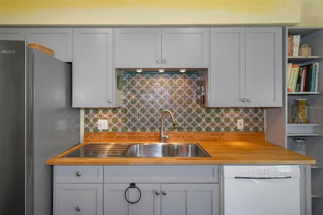 kitchen with dishwasher, backsplash, stainless steel fridge, white cabinetry, and butcher block counters