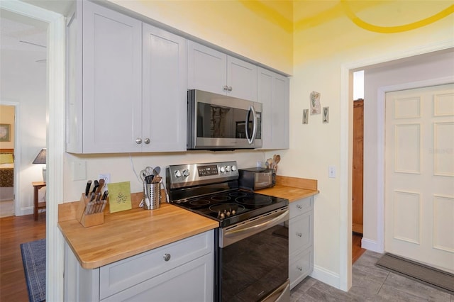 kitchen featuring white cabinetry, light wood-type flooring, appliances with stainless steel finishes, and wooden counters