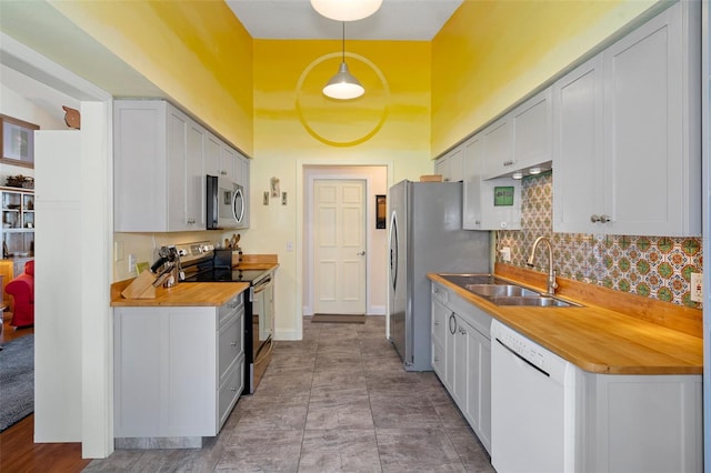 kitchen with sink, stainless steel appliances, tasteful backsplash, decorative light fixtures, and light tile patterned floors