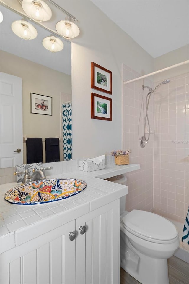 bathroom featuring wood-type flooring, vanity, toilet, and walk in shower