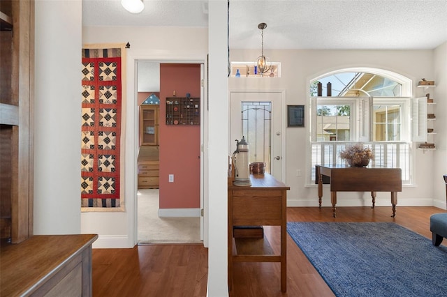 entryway featuring dark hardwood / wood-style flooring, a textured ceiling, and an inviting chandelier